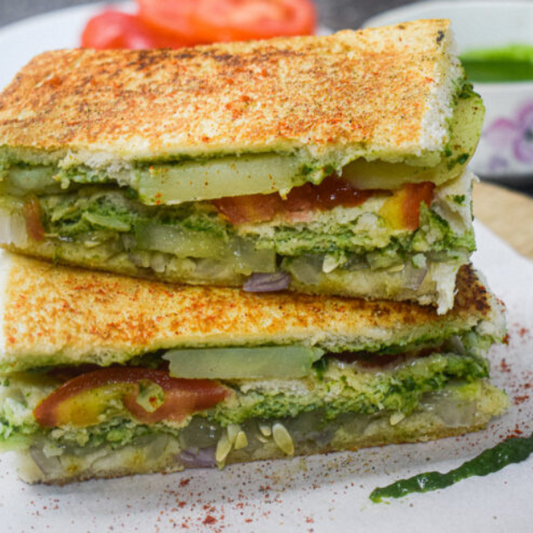 Closeup image of a Mumbai Veg Sandwich showing the inside stuffing of coriander chutney, onions, cucumber, tomato and potato.